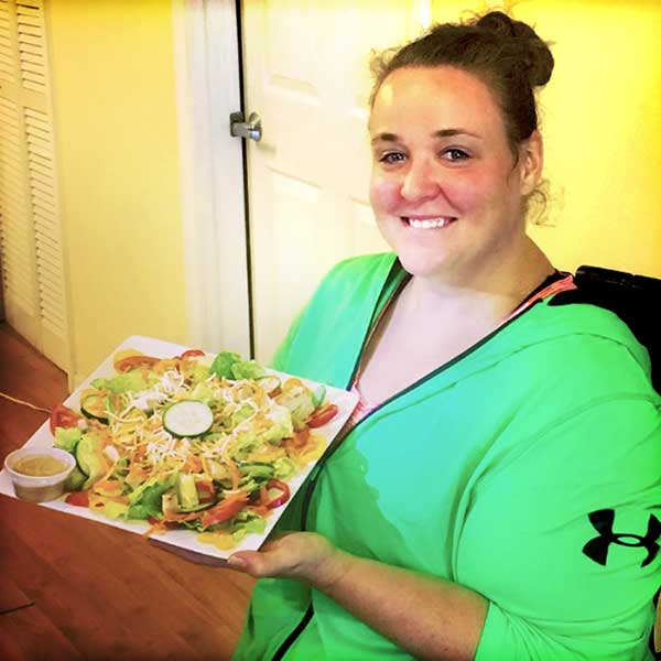 A happy weight loss retreat client showing off her meal at Weight Crafters.