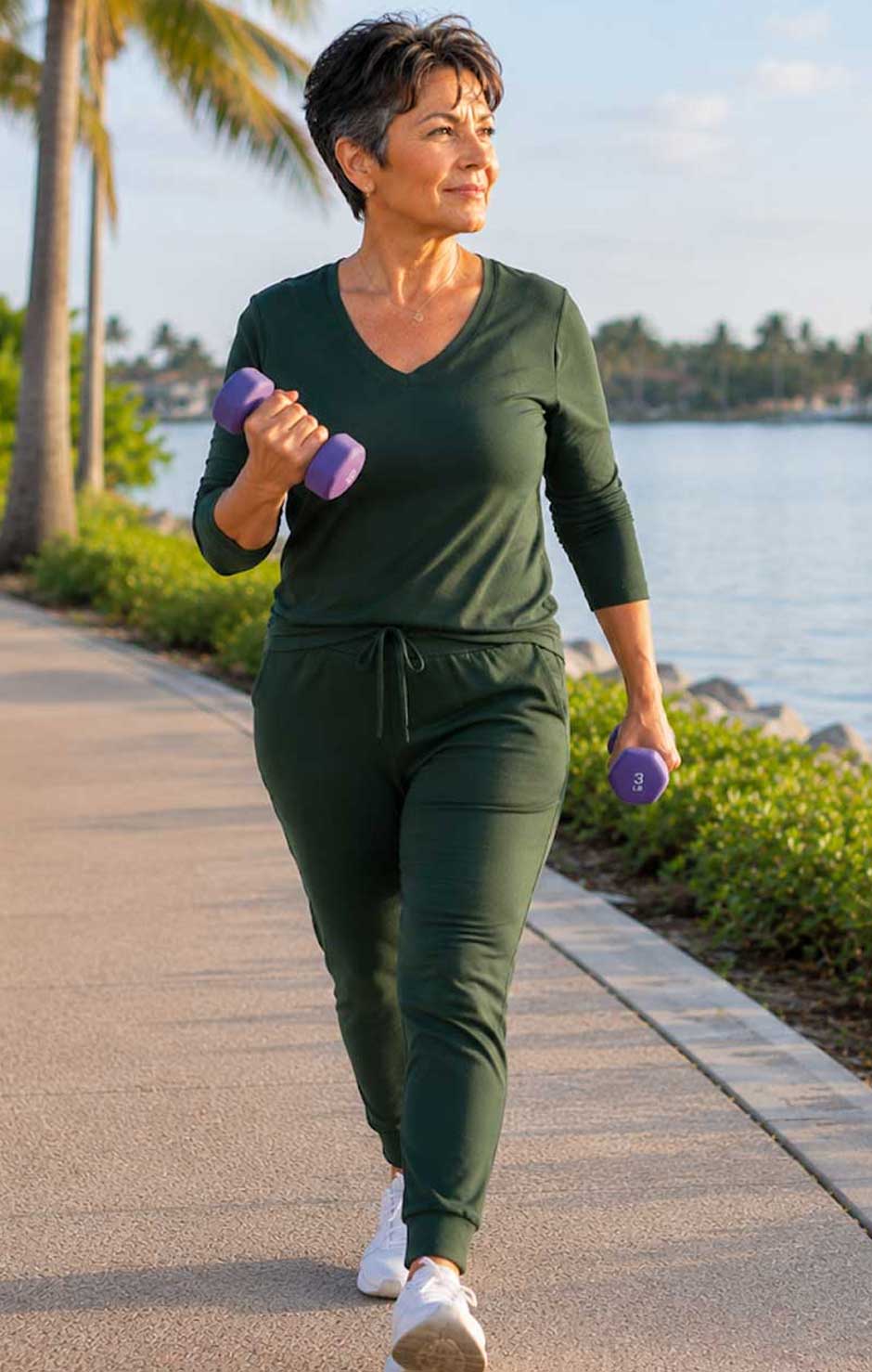 Woman performing a light dumbbell walking workout along the waterfront during a guided strength training for weight loss program in Florida